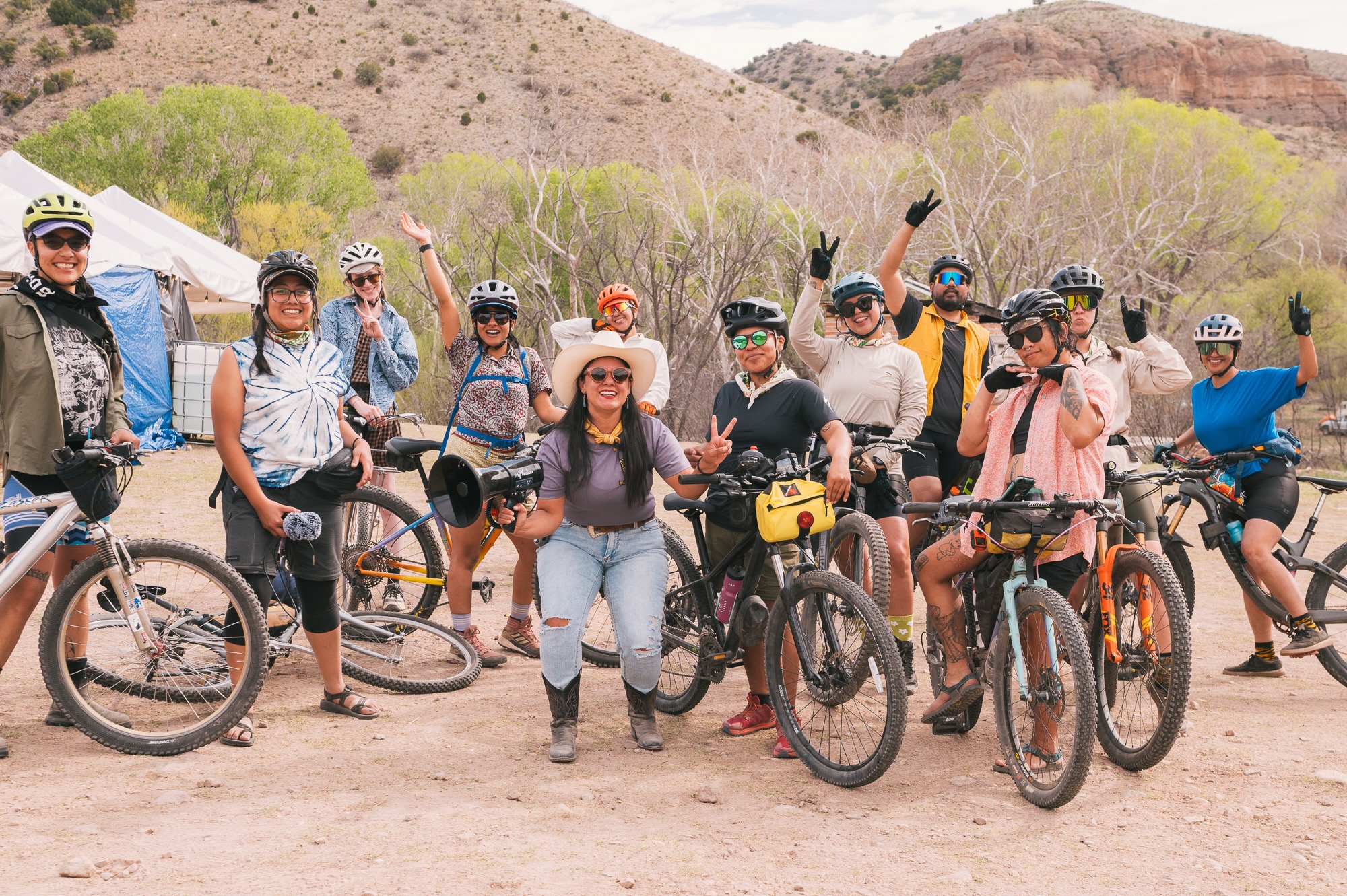 A group of people with bikes pose for a photo in the desert.